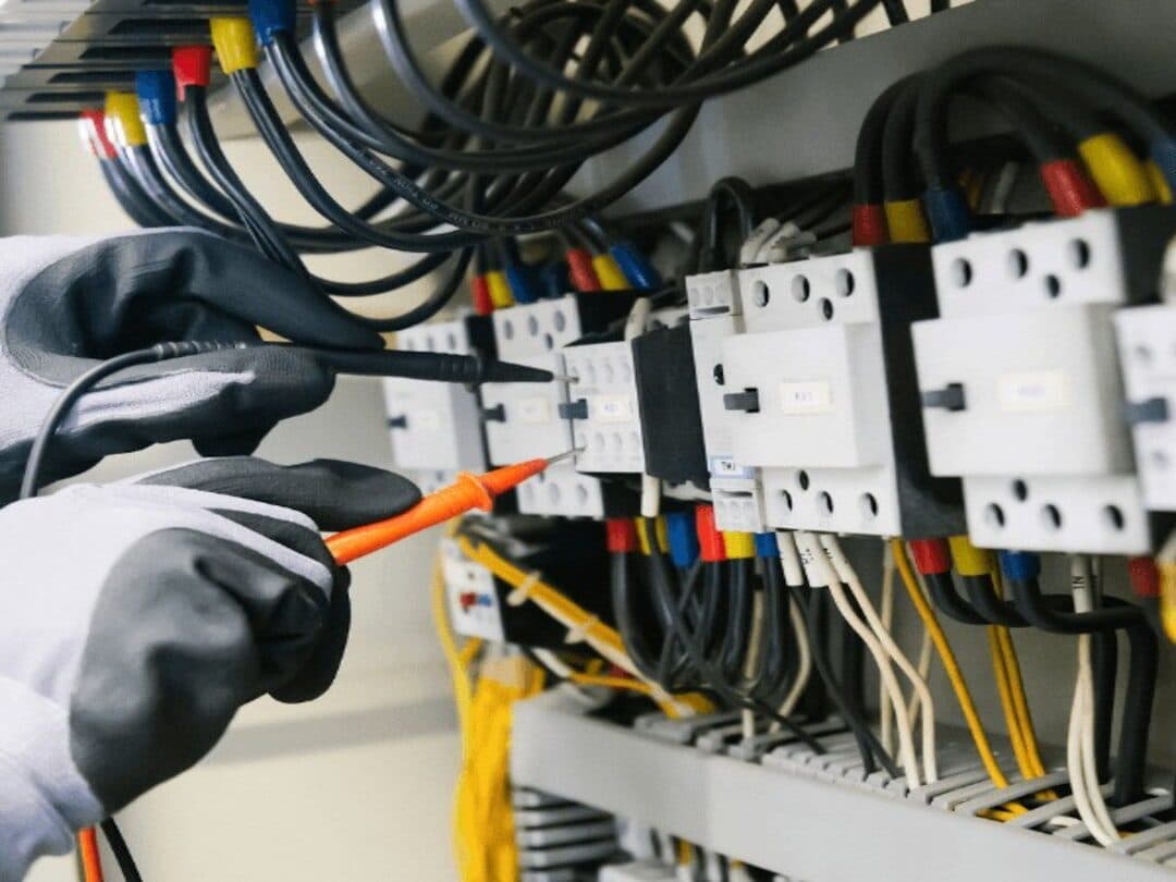 Technicien contrôlant le câblage d'une armoire de commande d'ascenseur